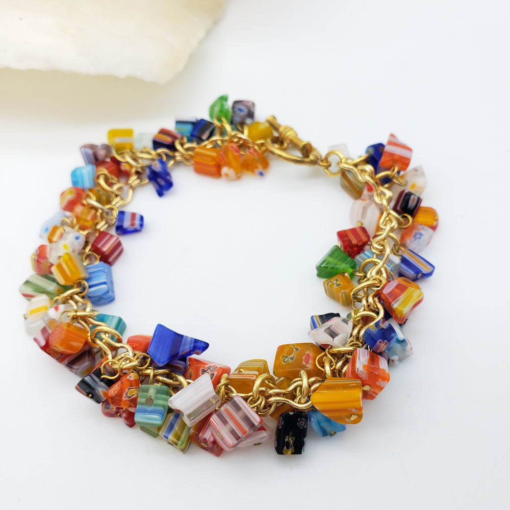 Colorful beaded bracelet with gold chain on a white background