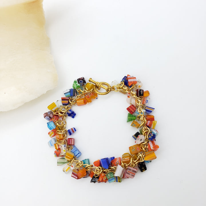 Colorful beaded bracelet with gold chain on a white background