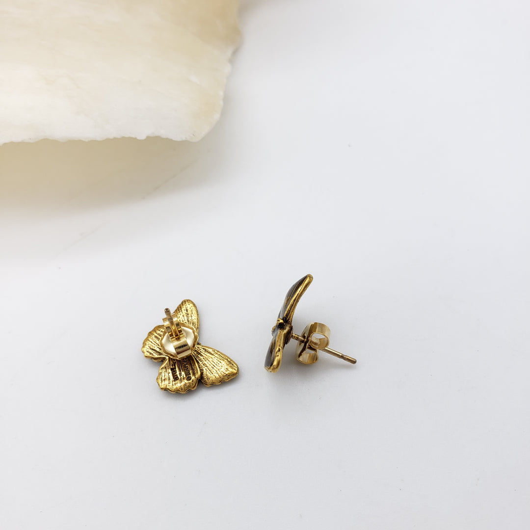 A pair of small gold butterfly stud earrings on a clean white background, with one earring showing the butterfly front and the other showing the post and backing.